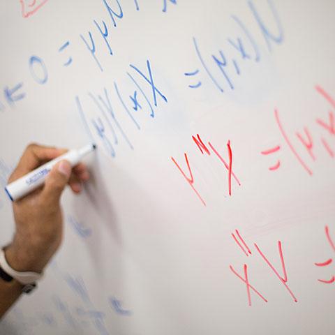 Math student writes equations on white board